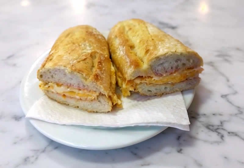 bocadillo de tortilla con queso en plato blanco sobre mesa de marmol